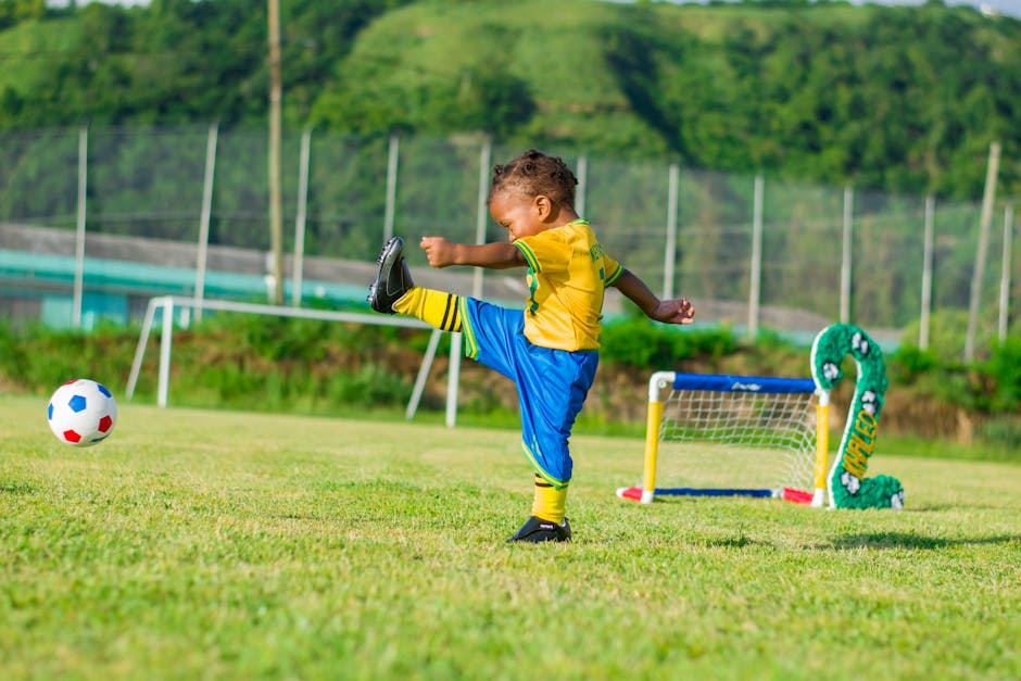 Young boy having fun playing soccer on a vibrant green field in Dominica.